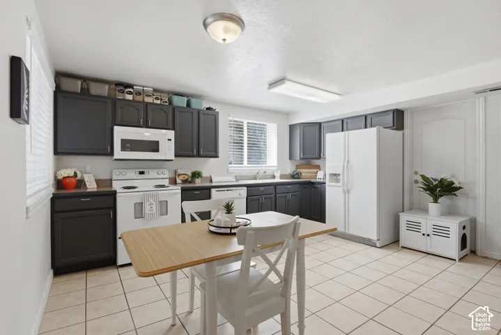 Kitchen window offers natural light highlighting the smooth tile flooring and dark custom cabinets.