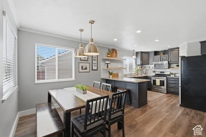 Open-concept kitchen and dining area featuring wood-finish flooring, dark contrasting cabinets.