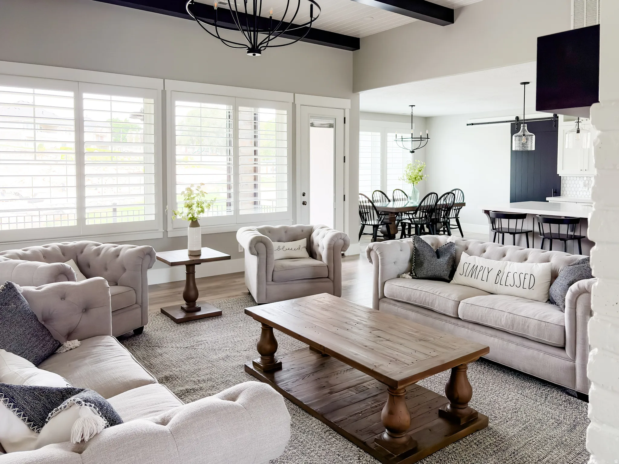 Open concept living area featuring a vaulted ceiling with exposed dark wood beams and a contemporary chandelier