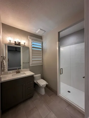 Bathroom featuring a single vanity with a white countertop and dark cabinetry, a framed mirror, and contemporary lighting