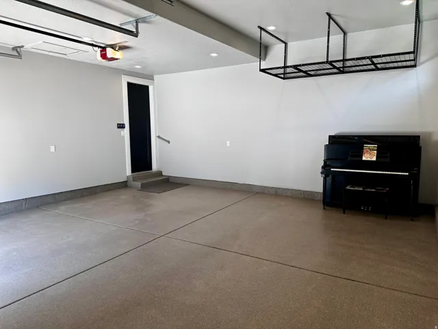 Spacious garage featuring a finished epoxy floor, recessed lighting, and an overhead storage rack
