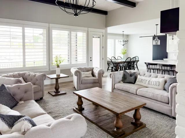 Open concept living area featuring a vaulted ceiling with exposed dark wood beams and a contemporary chandelier