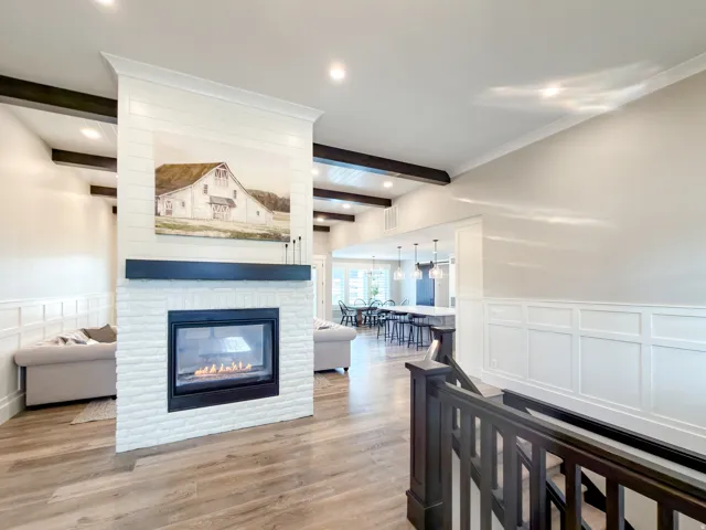 Central white brick fireplace with a black mantel and shiplap detailing