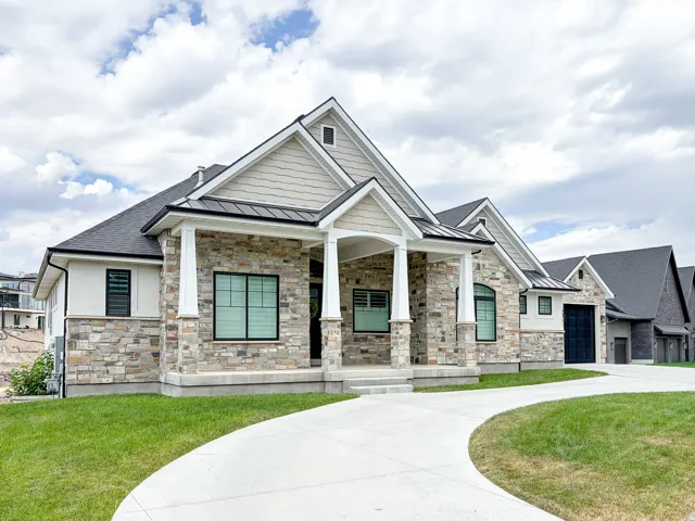 Stone and stucco exterior featuring multiple gables and a covered entry