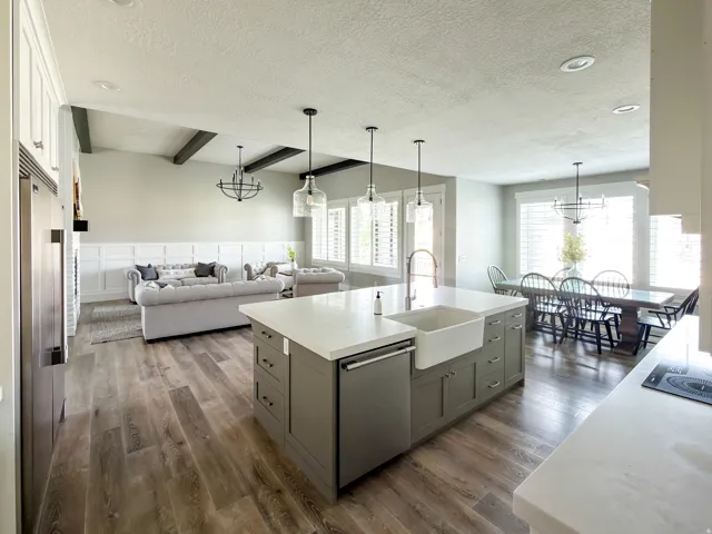 Kitchen island with white countertop and integrated farmhouse sink, framed by three pendant lights
