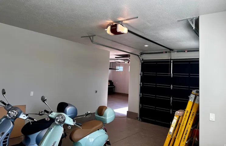 Spacious garage featuring a black overhead door, automatic opener, and light gray walls