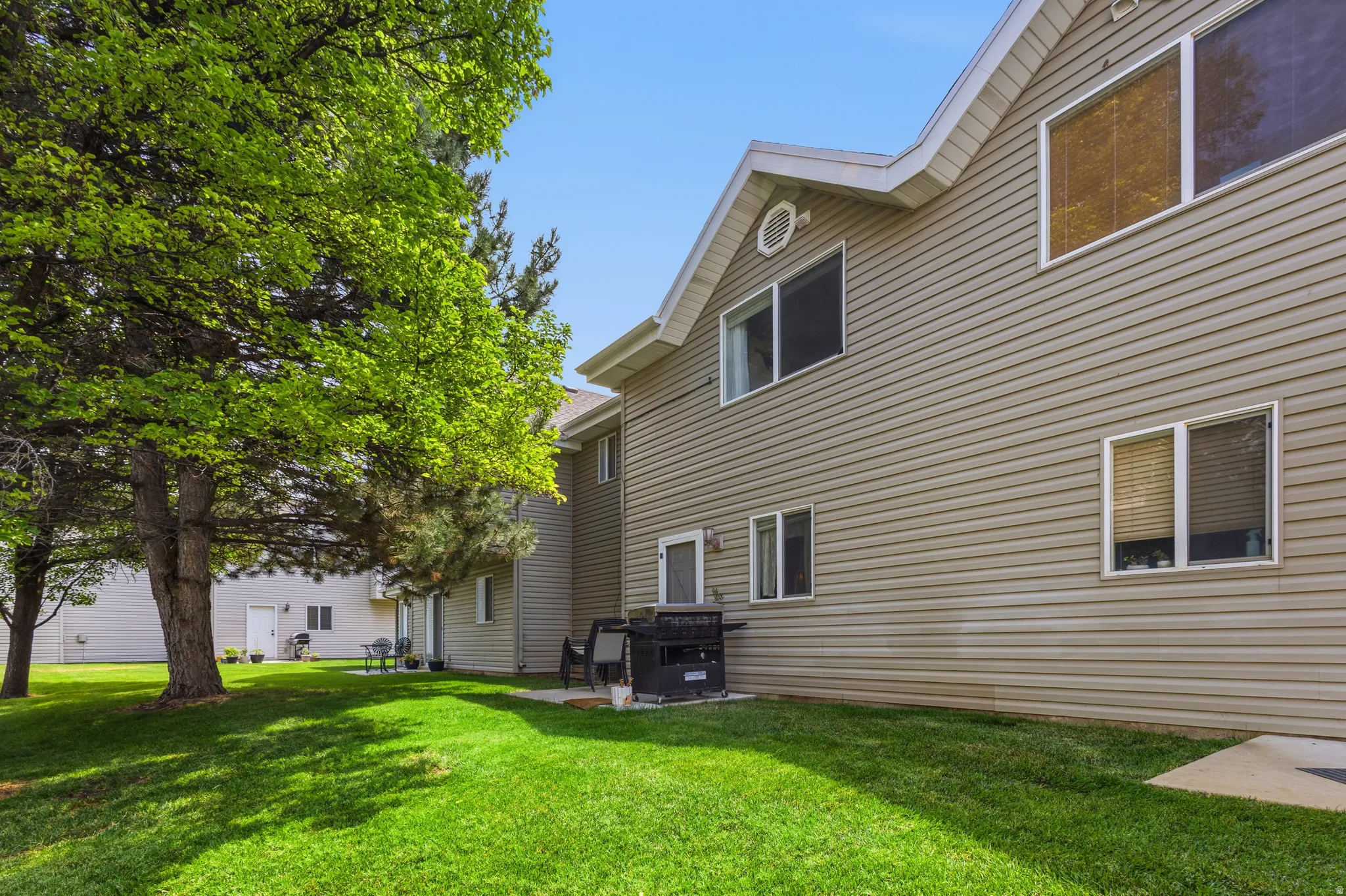 Manicured lawn with mature trees and a concrete patio