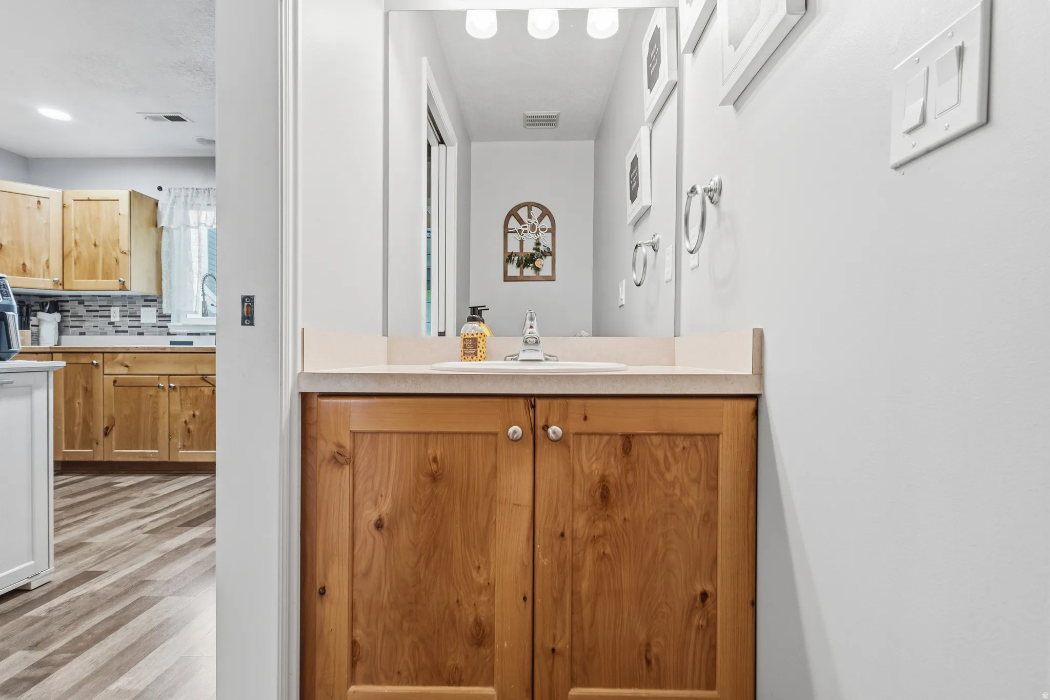 Bathroom vanity with a light-toned countertop, integrated sink, and wood-panel cabinetry