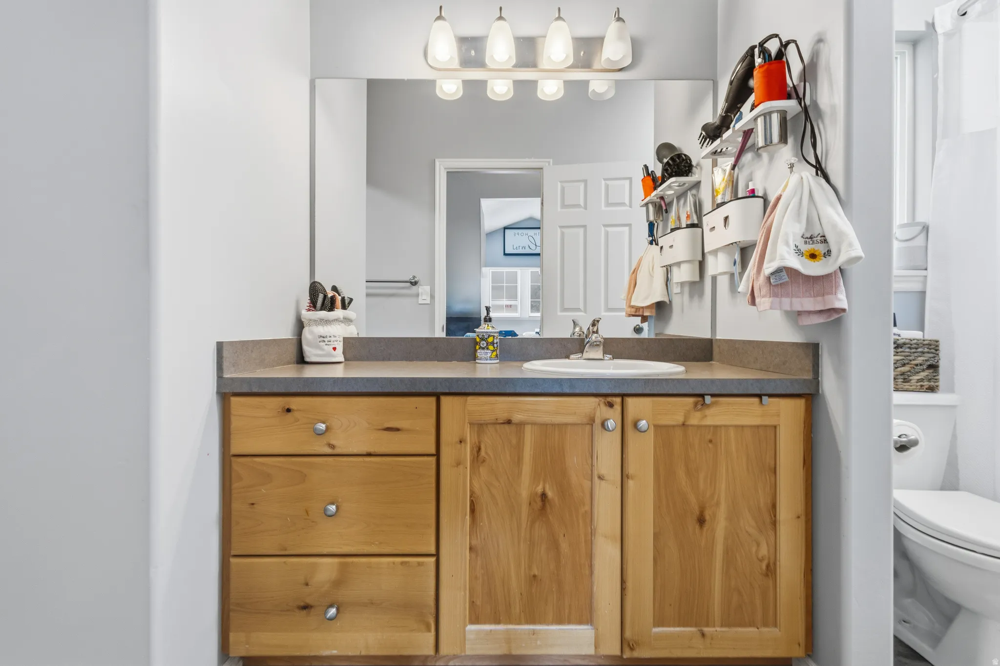 Vanity featuring a light wood-finish cabinet with three drawers and two doors, a light-colored countertop, and a built-in sink with a chrome faucet