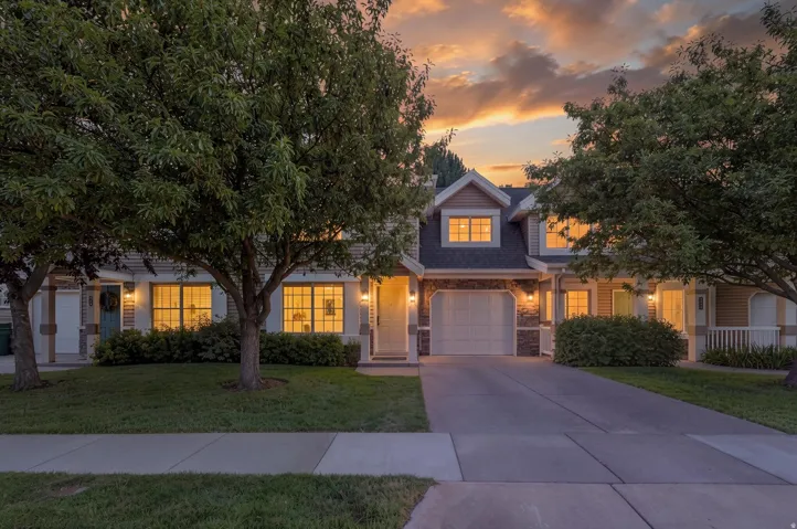 Inviting exterior featuring a prominent 1-car garage, dormer windows, a concrete driveway, established trees, and manicured landscaping