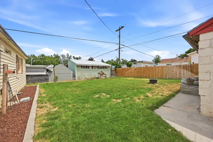 Expansive rear yard featuring a lawn area, wood privacy fencing, and a concrete patio