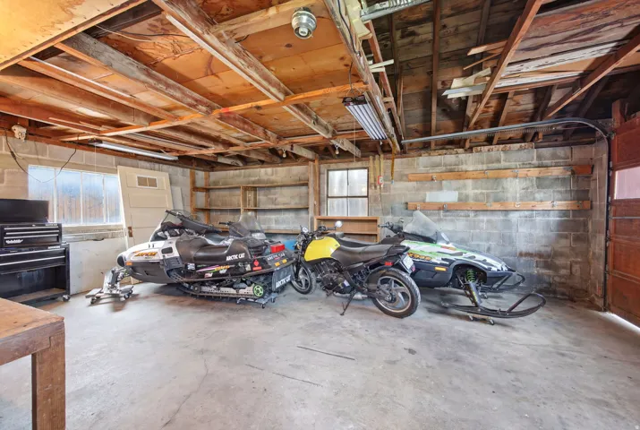 Spacious garage with concrete block walls, exposed wood beam ceiling, and a concrete floor