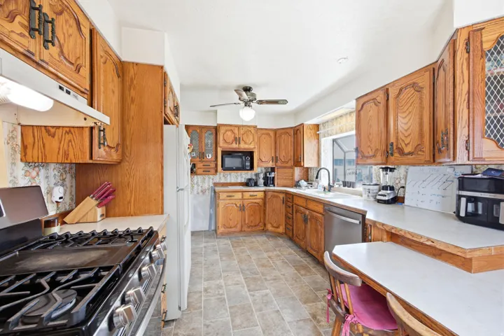Kitchen featuring ample wood cabinetry, white countertops, stainless steel dishwasher, and tiled flooring