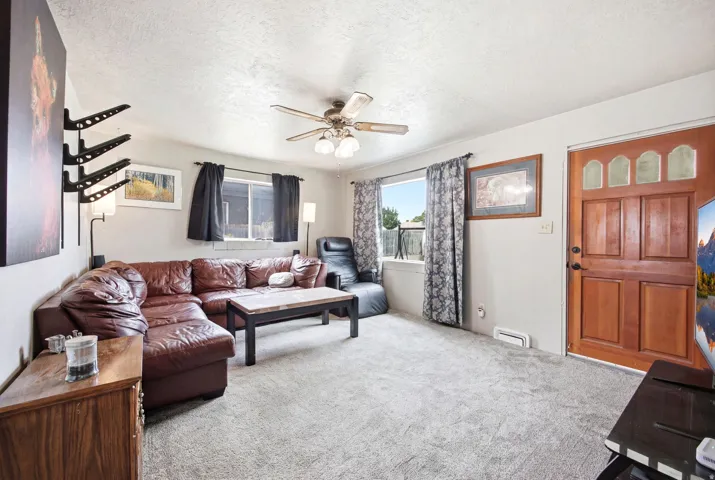Living area featuring a textured ceiling, ceiling fan, and light gray carpeting