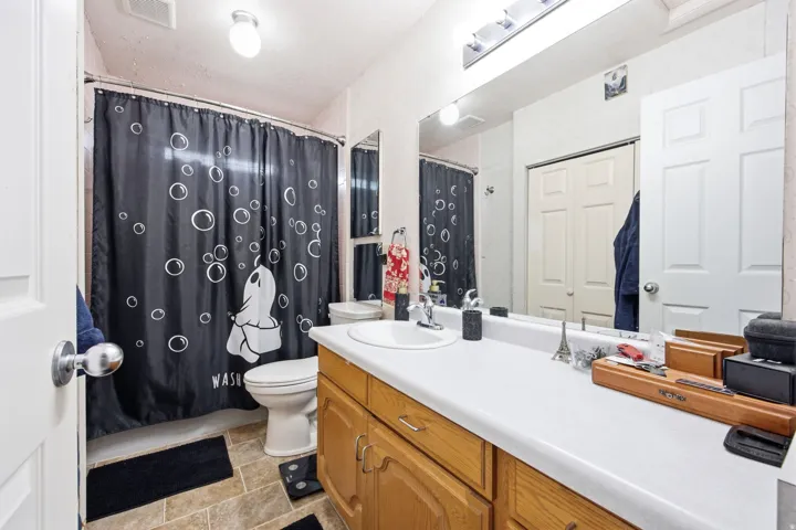 Bathroom featuring a tub/shower combination, a single vanity with wood-finish cabinetry, and a large wall-mounted mirror