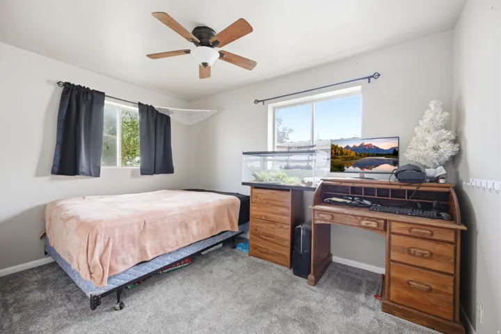 Room featuring light gray walls, gray carpet flooring, and a ceiling fan with integrated lighting