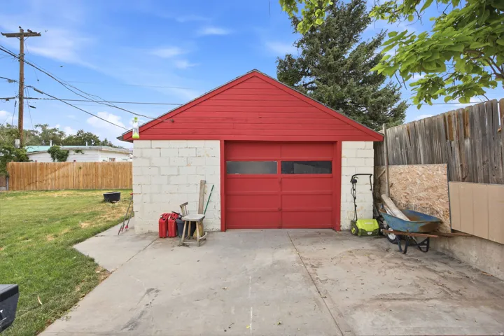 Detached garage featuring red siding, red garage door with transom windows, and white concrete block construction