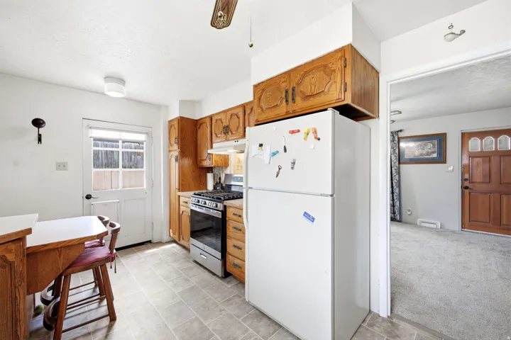 Kitchen with wood-finish cabinetry, stainless steel gas range, and light-toned flooring