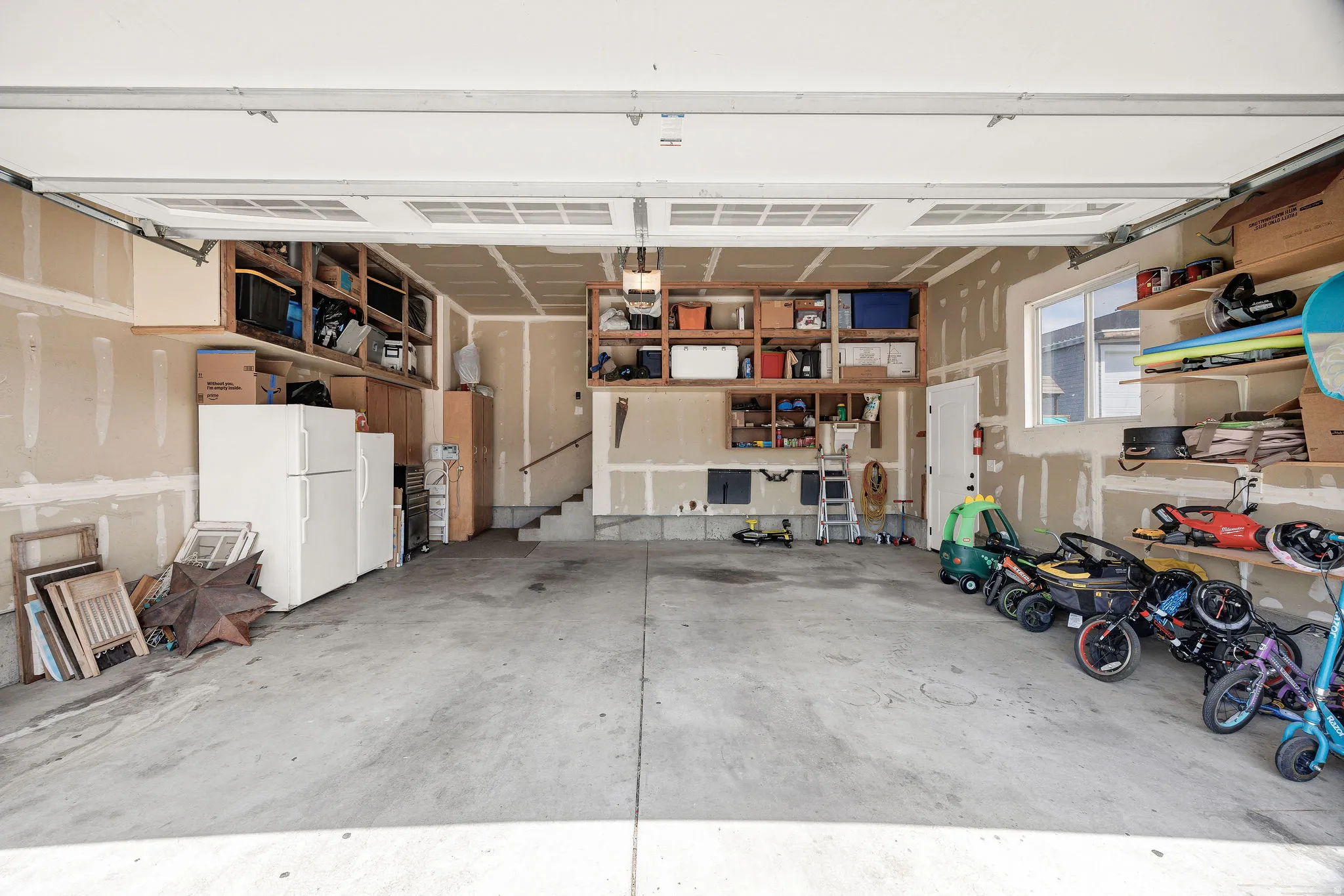 Spacious garage featuring a concrete floor, built-in shelving, an interior window, and an interior door