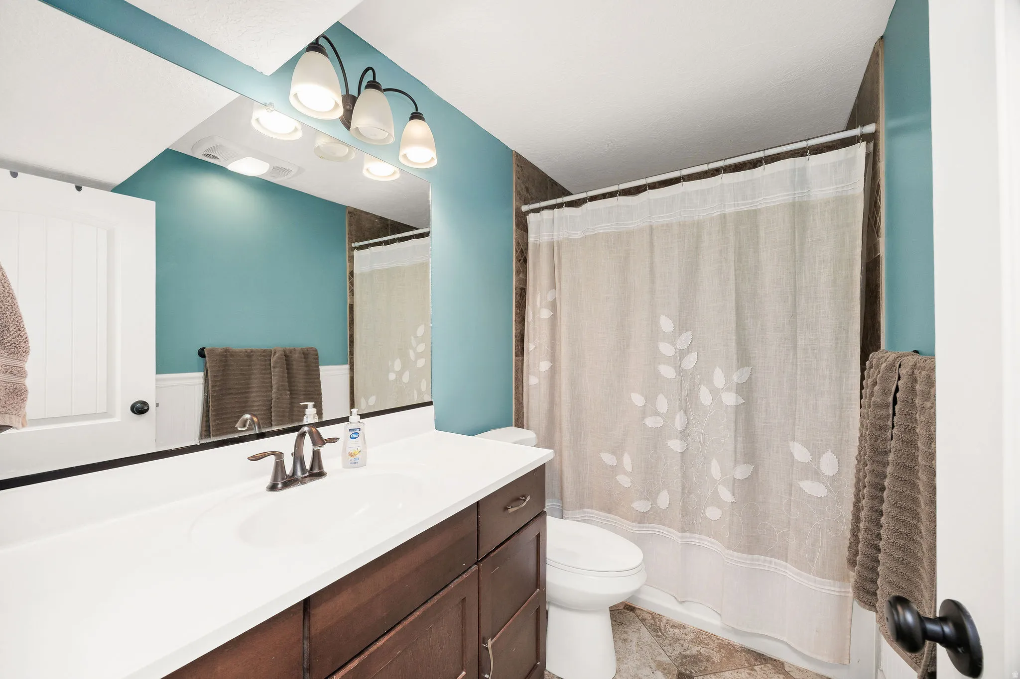 Bathroom featuring a single vanity with a white countertop, dark wood-finish cabinetry, and a bronze-finish faucet