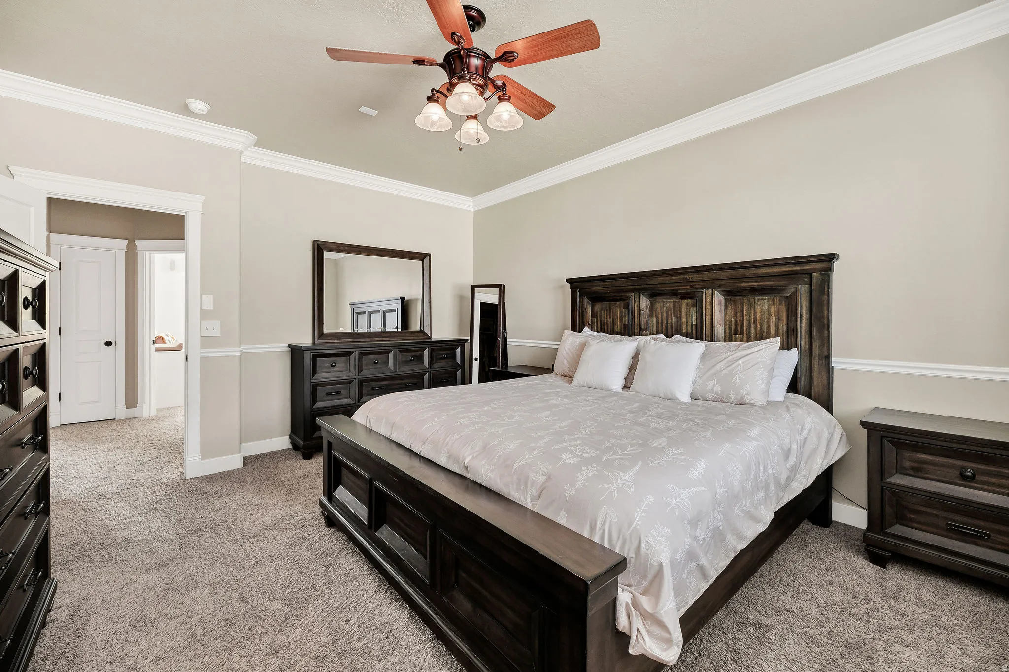 Spacious room featuring neutral wall tones, crown molding, and a ceiling fan with integrated lighting