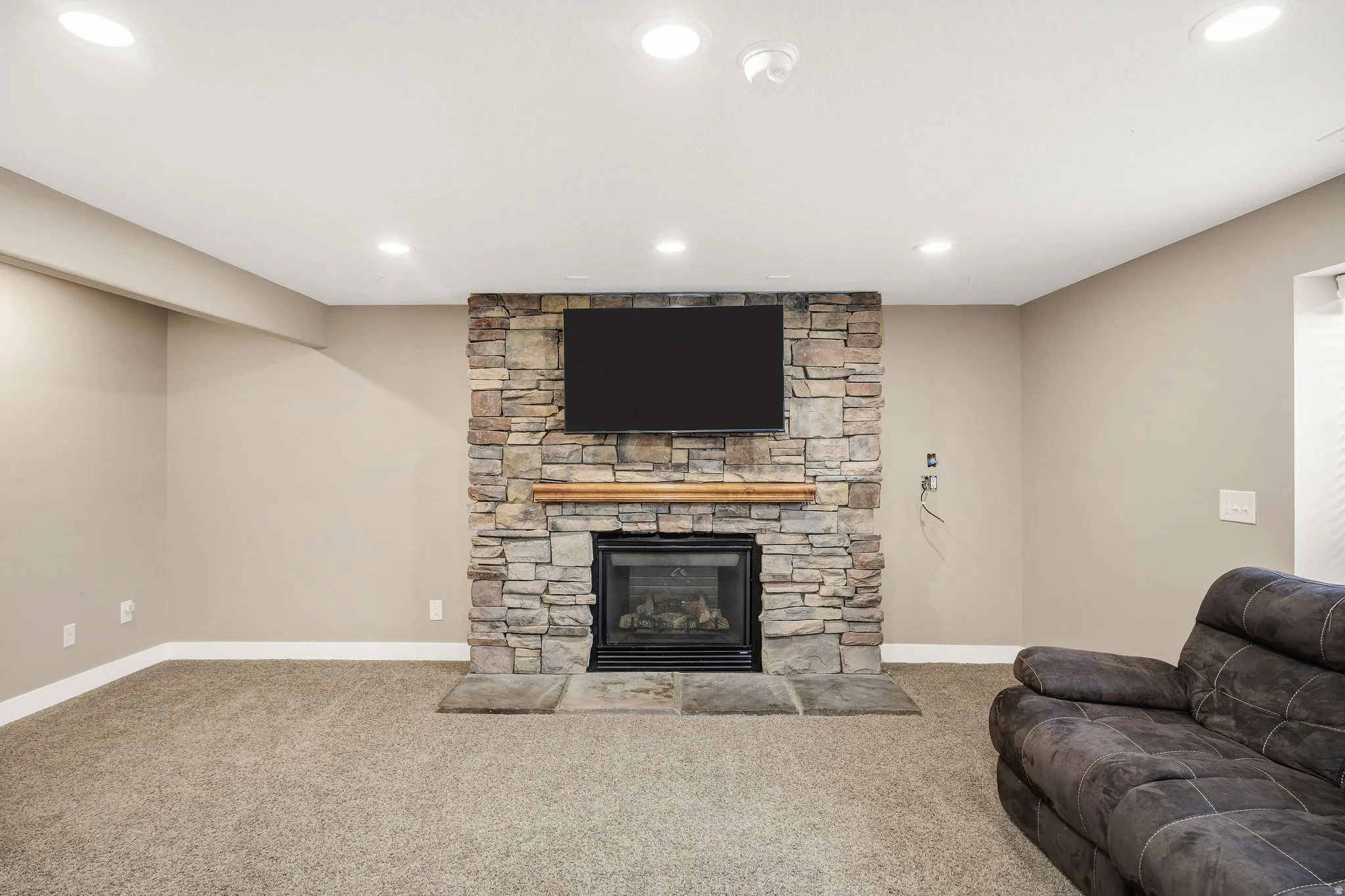 Stone-clad fireplace with a wood mantle, integrated hearth, and mounted display