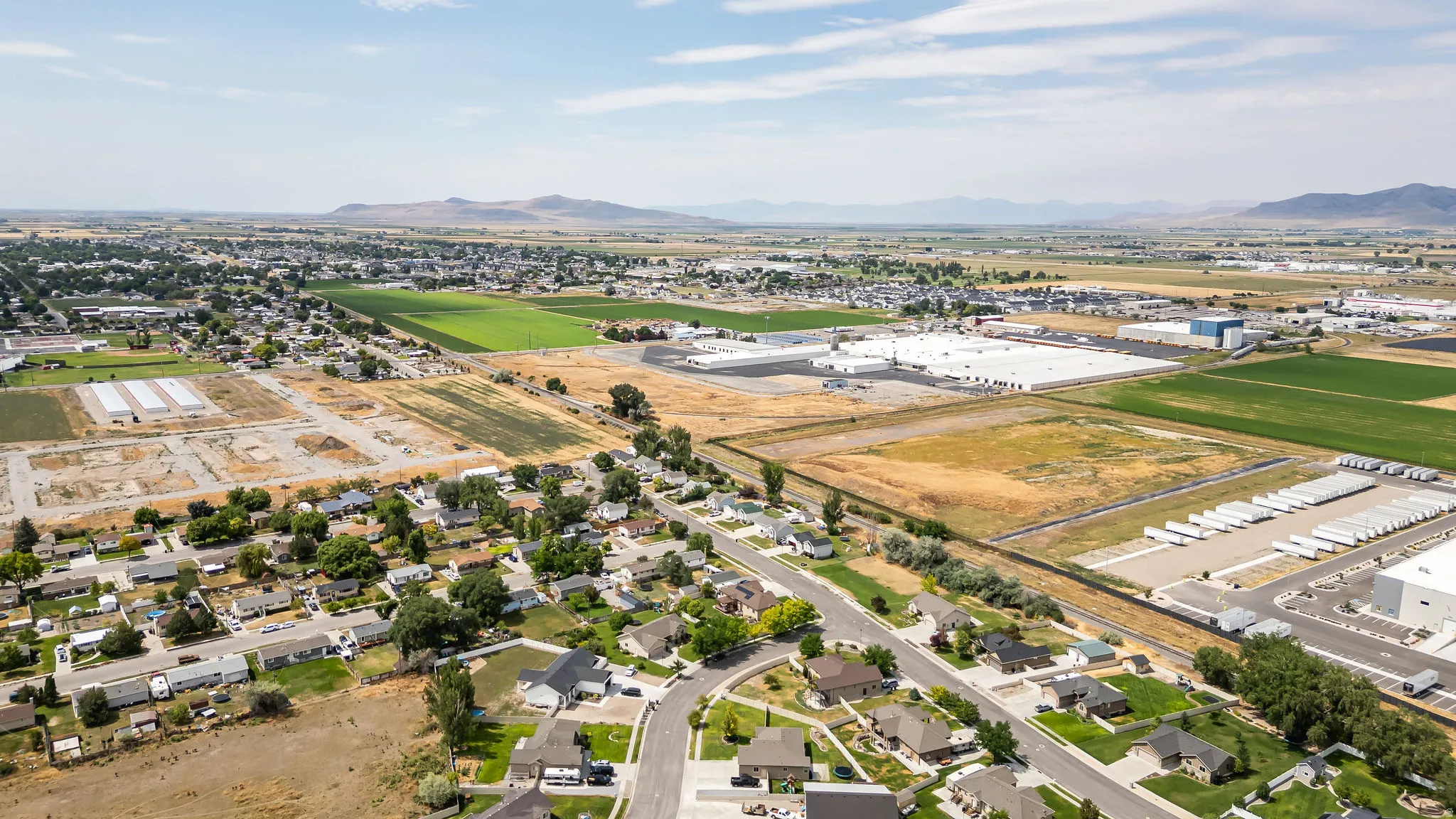 Expansive aerial view showcasing residential areas, agricultural fields, and commercial/industrial structures