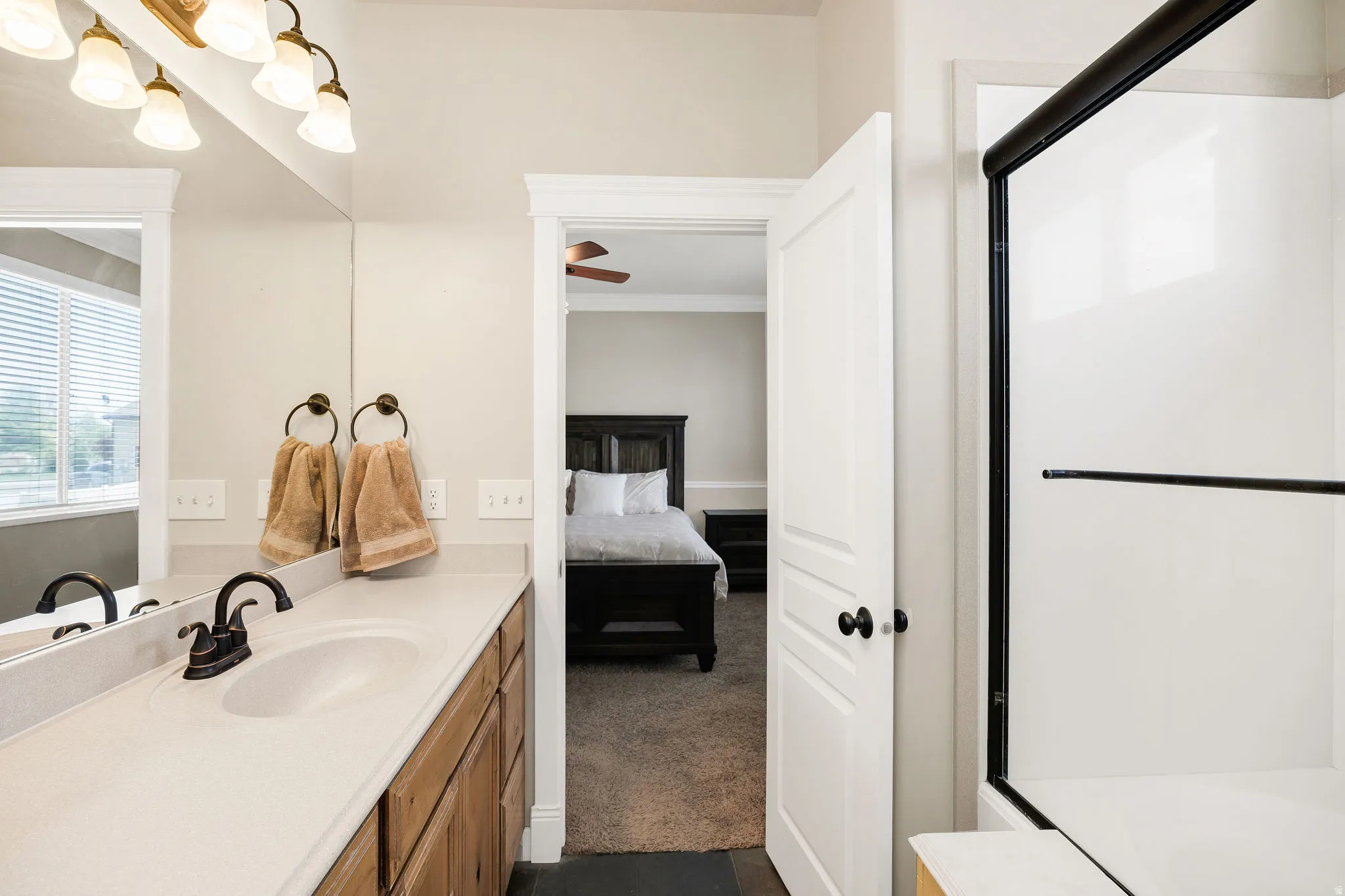 Bathroom vanity with an integrated white sink, bronze faucet, and wood-finish cabinetry