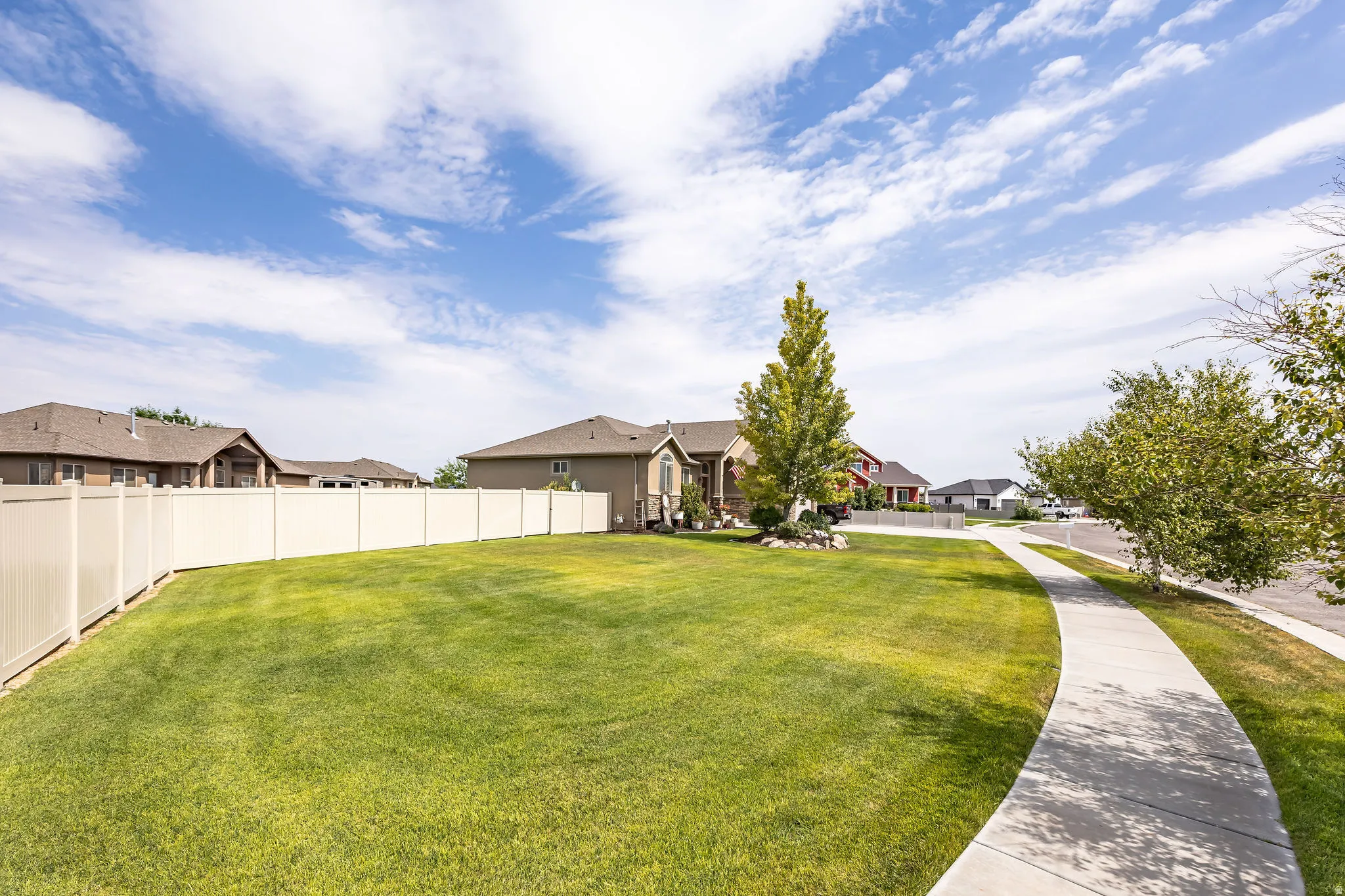 Expansive lawn area bordered by a light-toned privacy fence