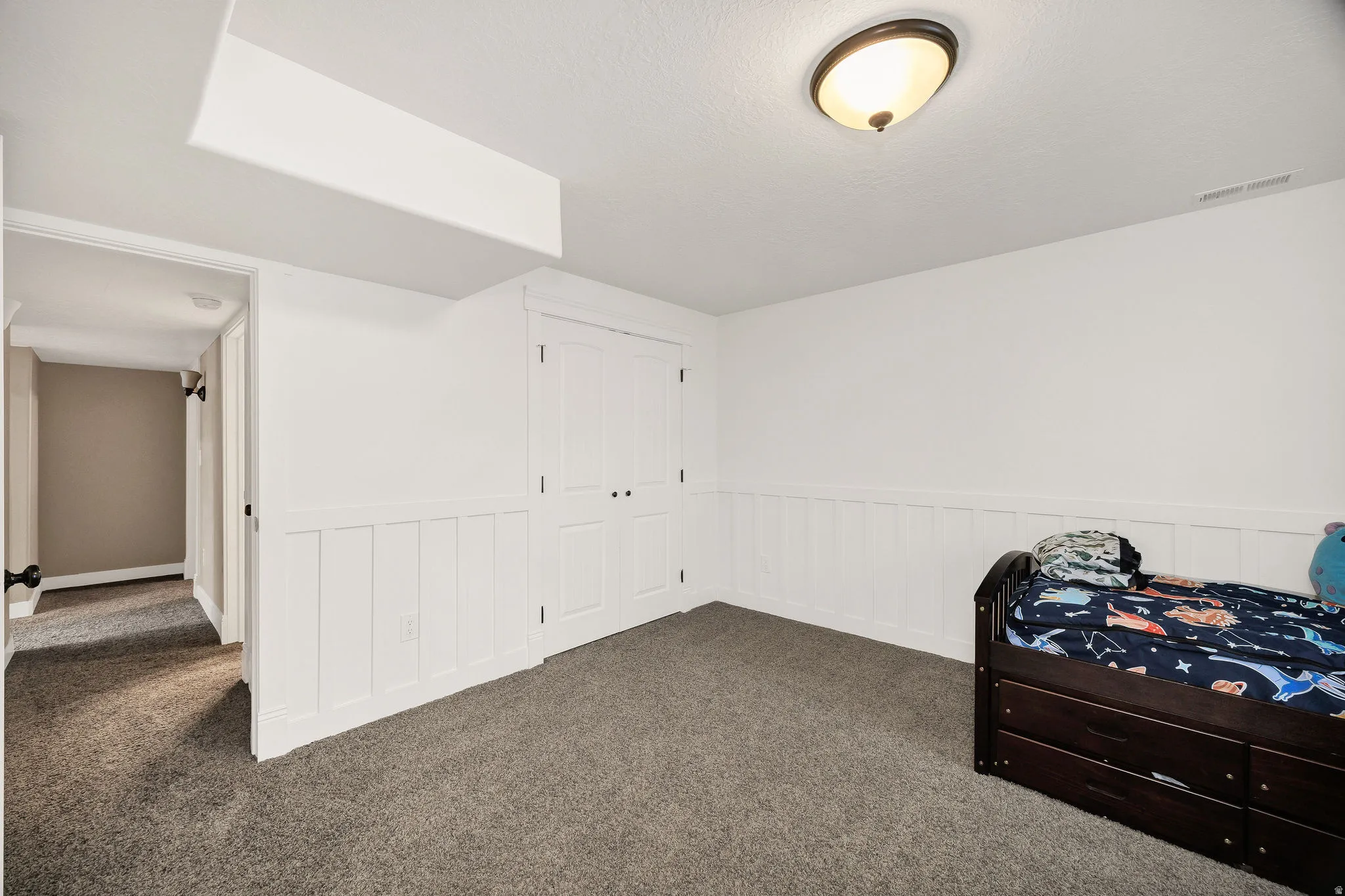 Room featuring dark gray carpet flooring, white walls, and board-and-batten wainscoting