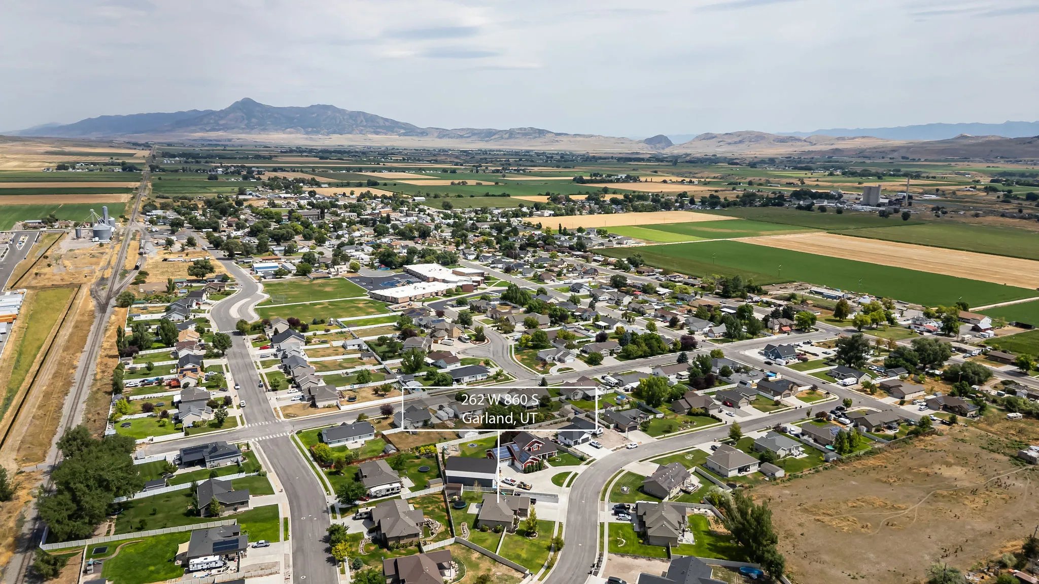 Aerial perspective showcasing a residential neighborhood with surrounding agricultural fields and distant mountains