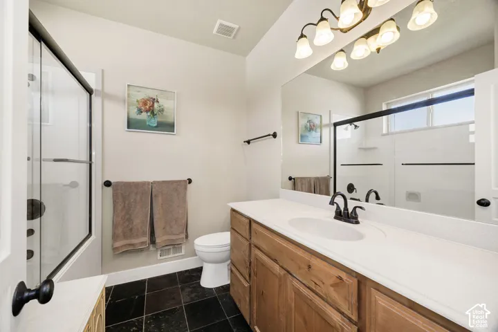 Bathroom featuring a wood-finish vanity with a white countertop, an integrated sink, and a dark bronze faucet