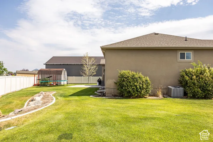 Expansive backyard with a manicured lawn, white vinyl fencing, and a decorative rock garden feature