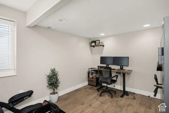 Versatile interior space featuring wood-finish flooring, recessed lighting, and a single window with blinds