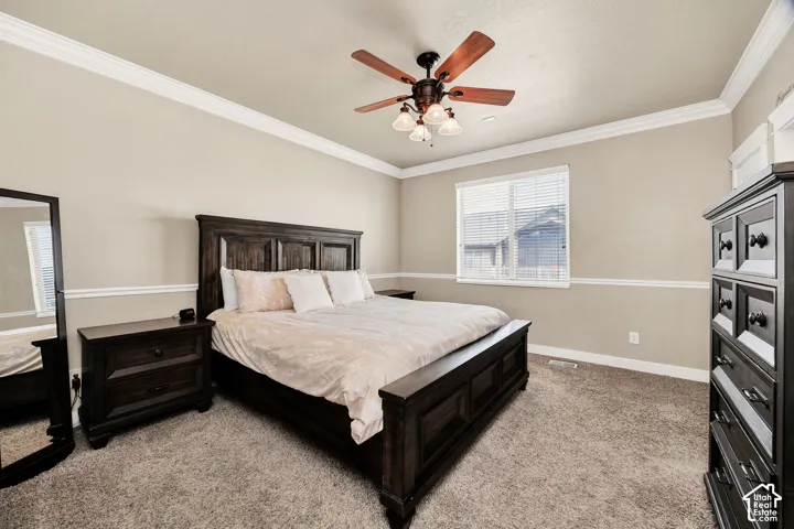 Carpeted interior space featuring a window with blinds, crown molding, a ceiling fan with integrated lighting, and chair rail molding