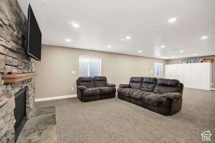 Spacious living area featuring a stacked stone fireplace with a wood mantle, recessed lighting, neutral wall tones, and built-in white cabinetry