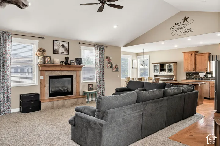 Vaulted ceilings above a carpeted living space featuring a fireplace with a wood mantle and stone surround