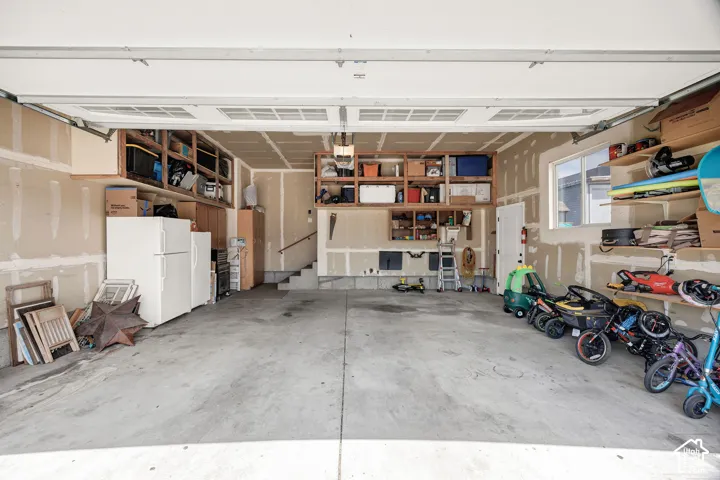 Spacious garage featuring a concrete floor, built-in shelving, an interior window, and an interior door