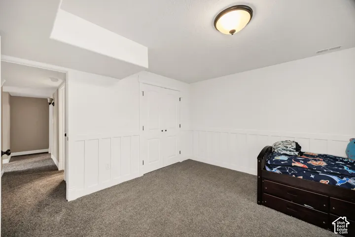 Room featuring dark gray carpet flooring, white walls, and board-and-batten wainscoting