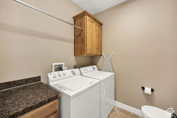 Dedicated laundry area featuring a wood-finish upper cabinet, a horizontal hanging rod, and a speckled dark countertop