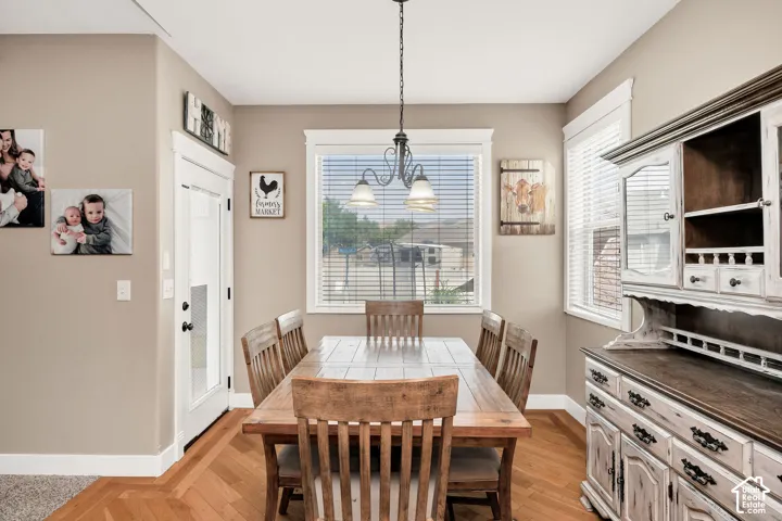 Dedicated dining area featuring wood-finish flooring in a herringbone pattern, neutral wall tones, and white trim