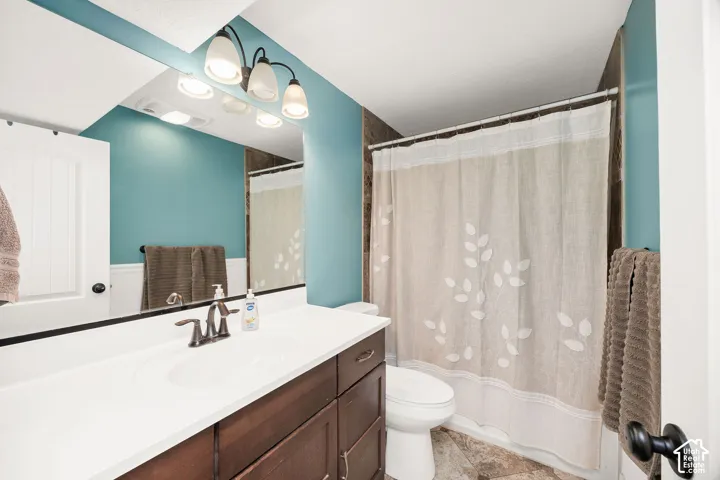 Bathroom featuring a single vanity with a white countertop, dark wood-finish cabinetry, and a bronze-finish faucet