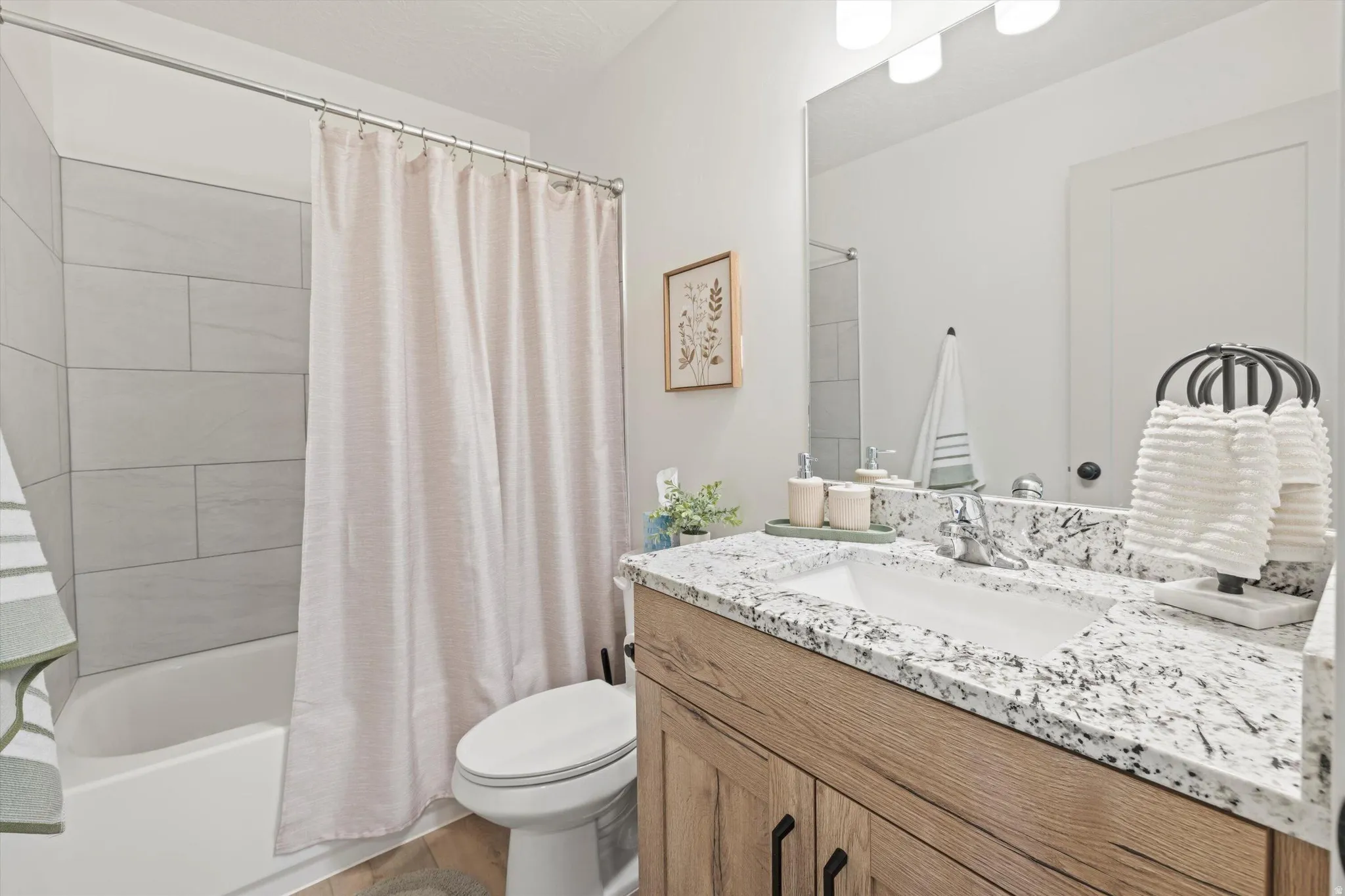 Bathroom featuring a full vanity with an integrated sink, a speckled countertop, and a wood-finish cabinet