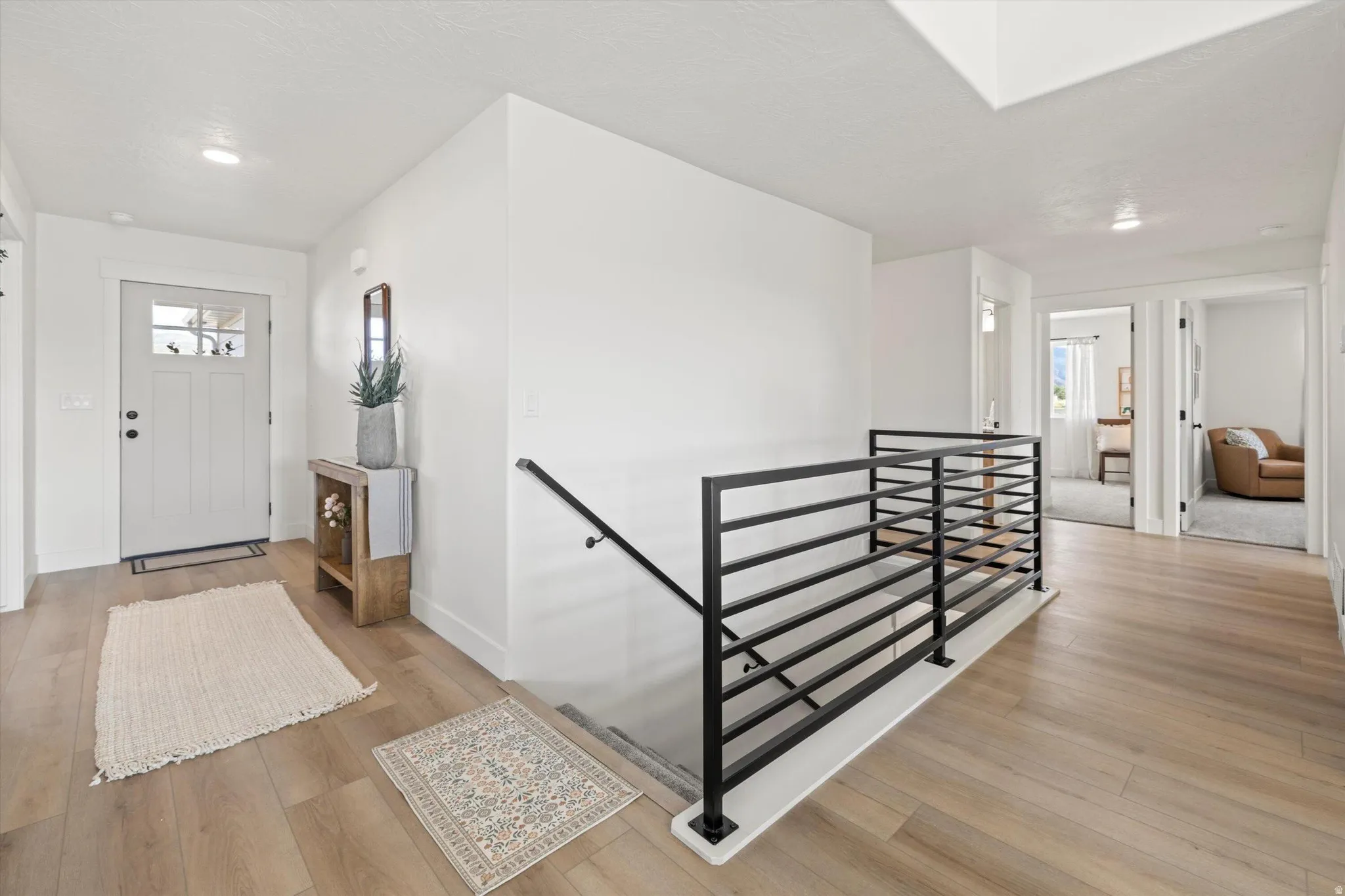 Bright entryway featuring a white paneled door with glass inserts, wood-finish flooring, and recessed lighting
