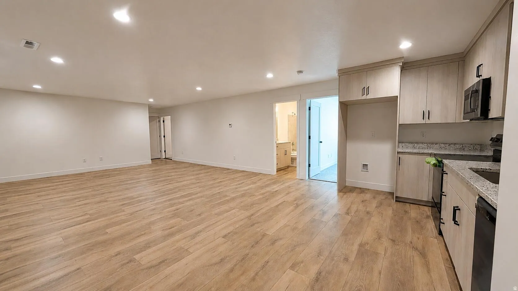 Open-concept living area with wood-finish flooring, recessed lighting, and white walls