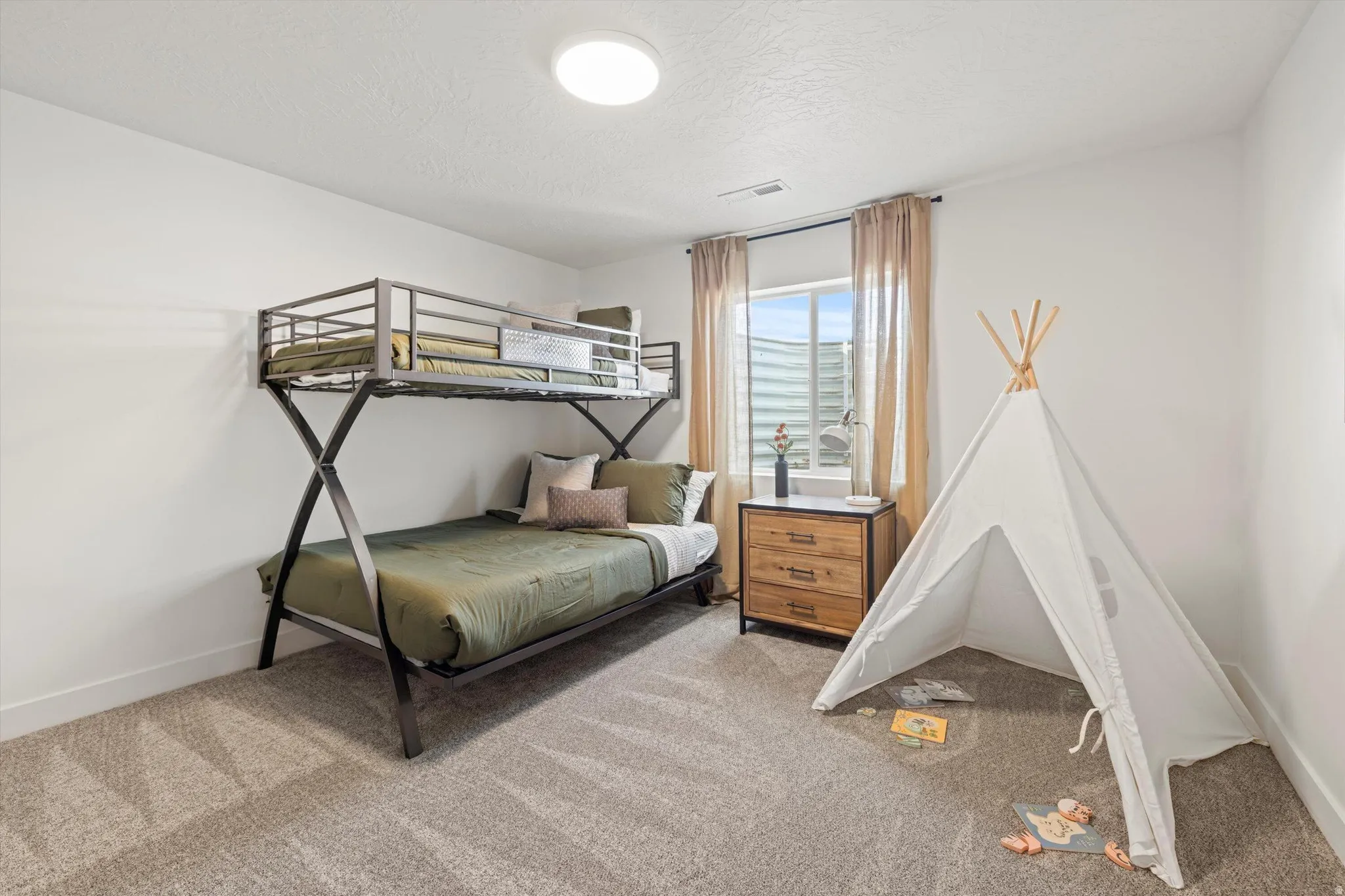 Carpeted room featuring a window with blinds and curtains, a built-in light fixture, and white painted walls