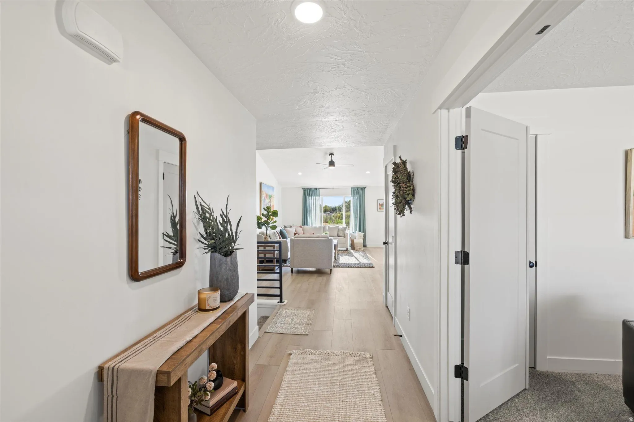 Bright hallway featuring light wood-finish flooring, recessed lighting, and white walls