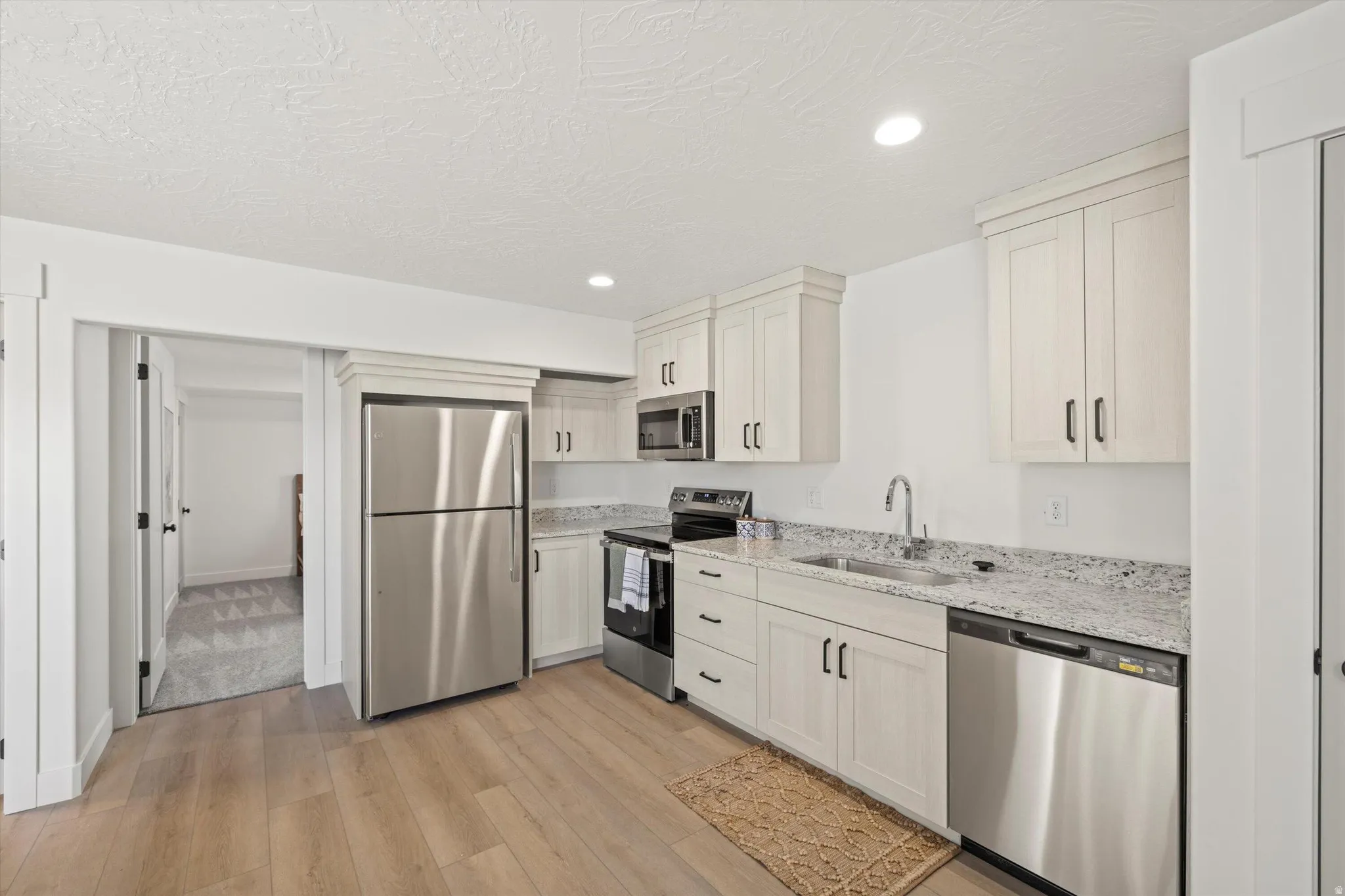 Contemporary kitchen featuring light wood-finish cabinetry and stainless steel appliances