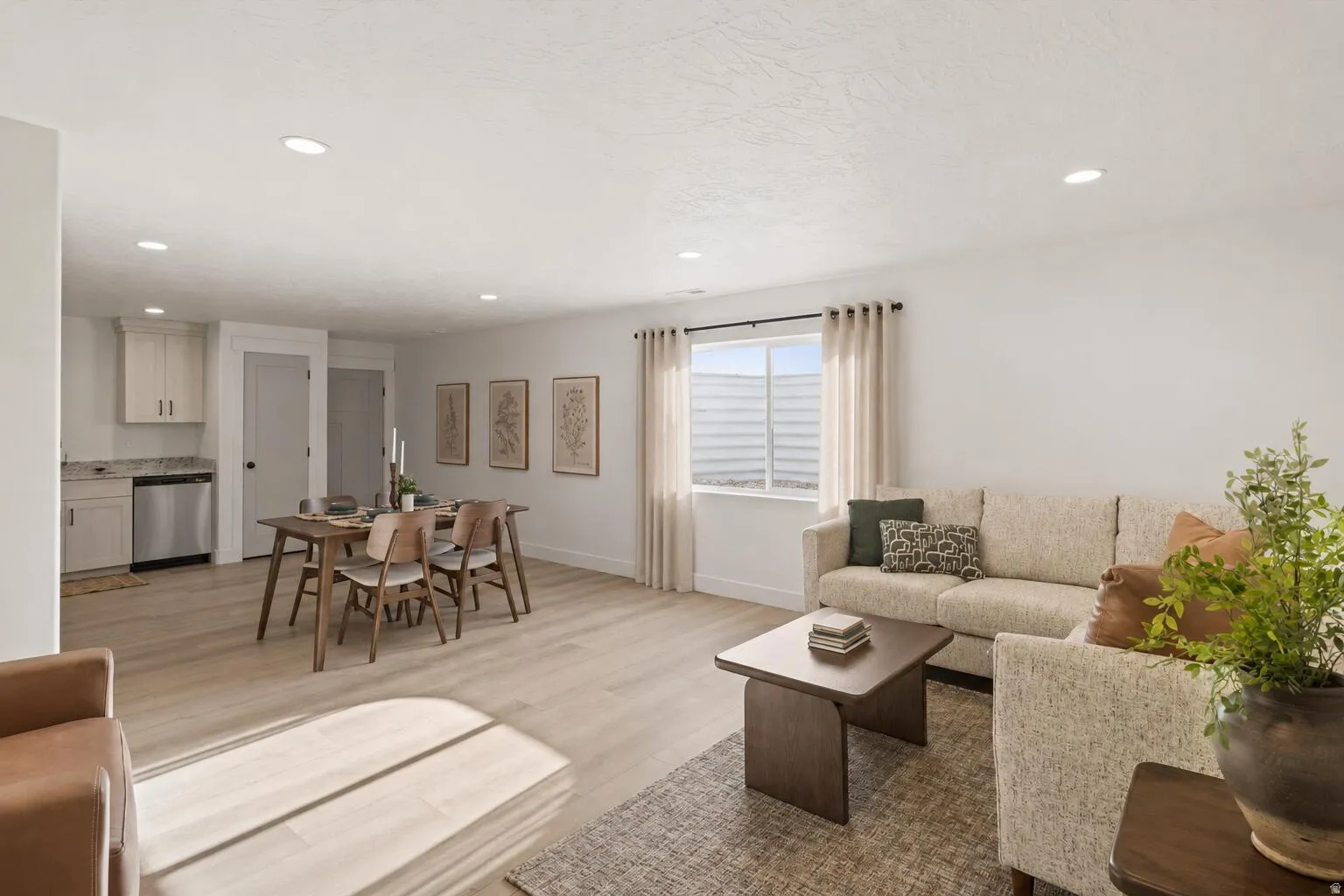 Open-concept living space featuring wood-finish flooring, recessed lighting, and a modern kitchen area with stainless steel appliances