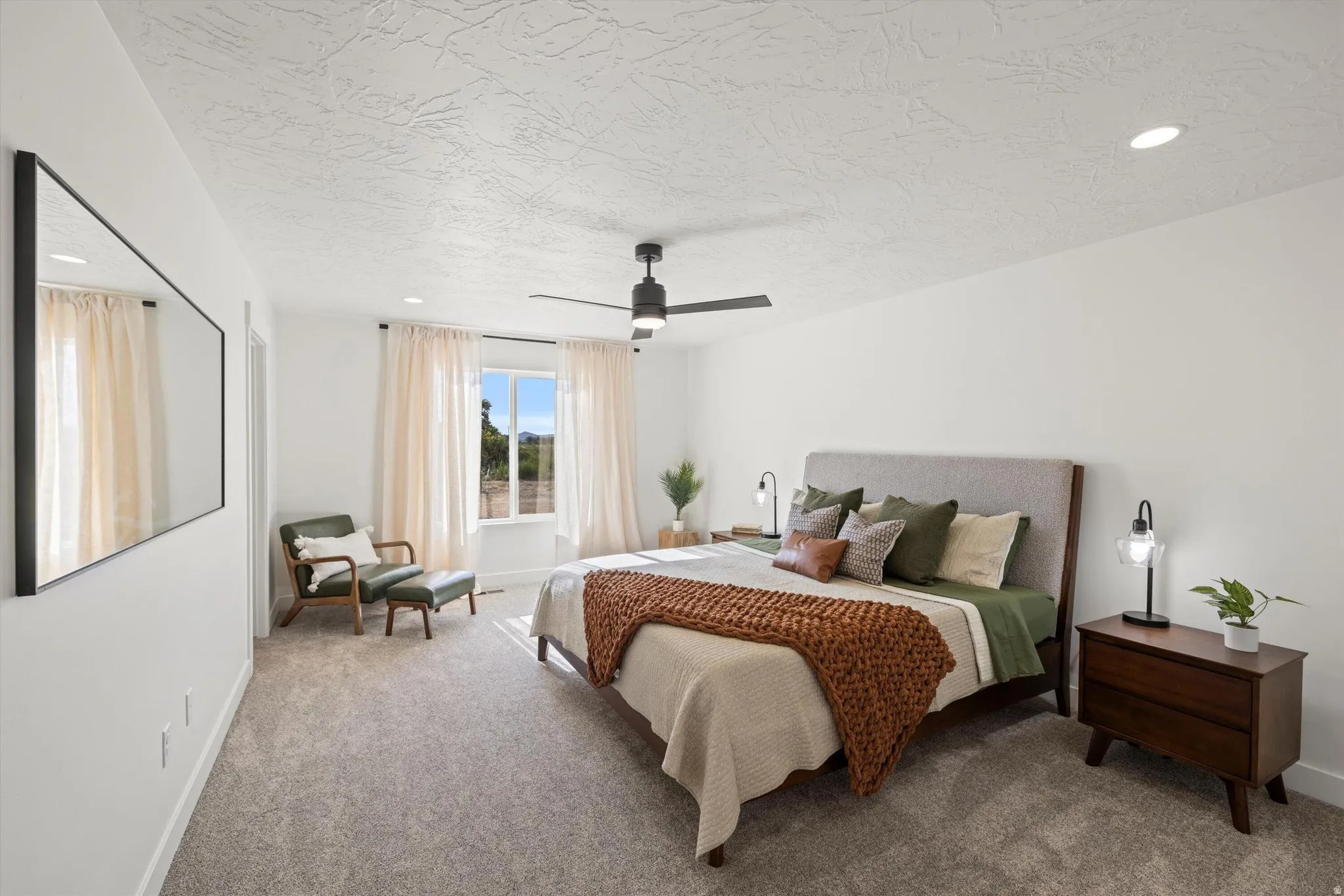 Carpeted room featuring white walls, a single window with light-colored drapes, and a ceiling fan with integrated lighting